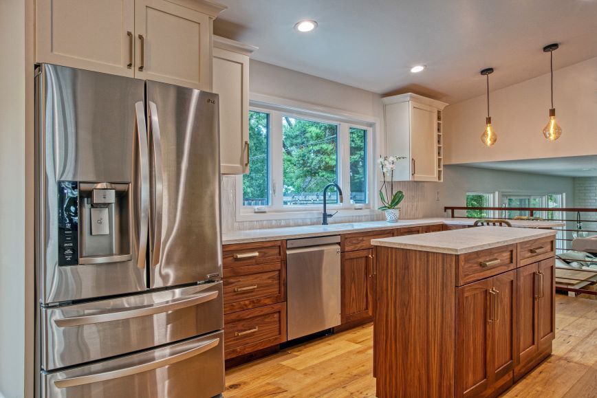 Modern kitchen with stainless steel appliances, wood cabinets, island, and a window over the sink