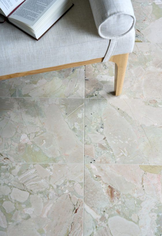 Light gray marble tile floor beside a sofa leg and an open book on the seat.