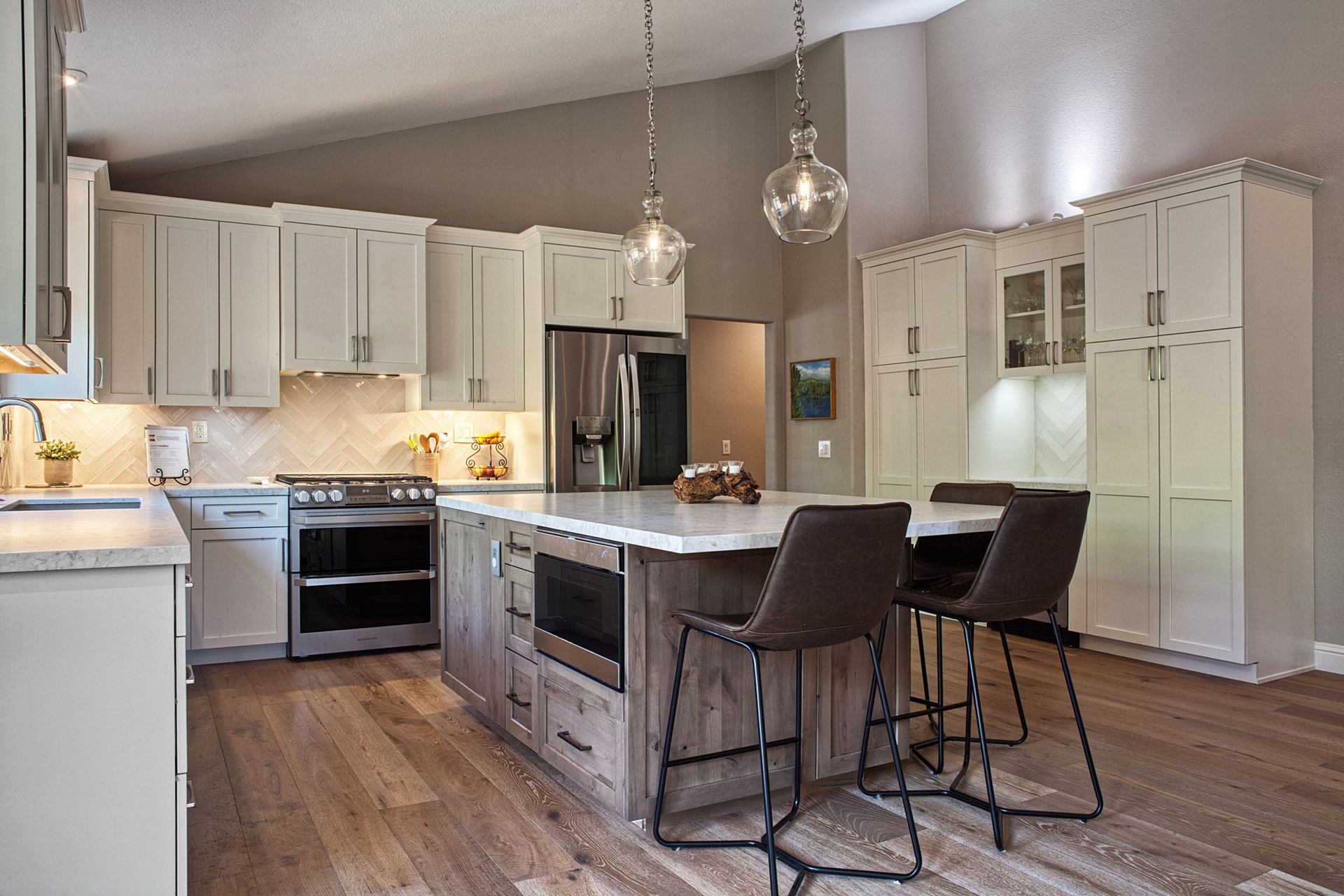 Bright modern kitchen with white cabinets, island seating, stainless appliances, and wood floors