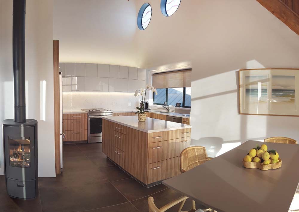 Modern kitchen and dining area with wood cabinets, white countertops, and a bowl of lemons on the table