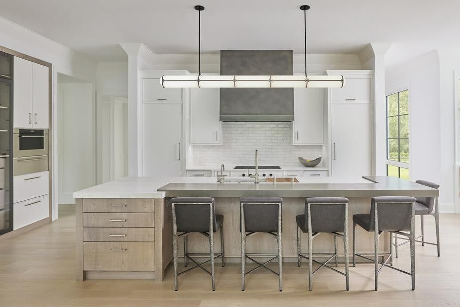 Bright modern kitchen with white cabinets, central island, bar stools, and pendant lights