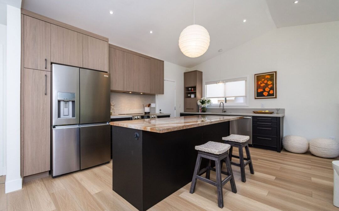 Modern kitchen with stainless fridge, black island, bar stools, and light wood floors
