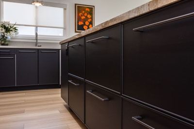 Modern kitchen with dark cabinets, light wood floor, and a window over the sink