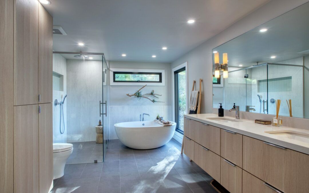 Modern bathroom with freestanding tub, glass shower, and double vanity in light wood and white finishes