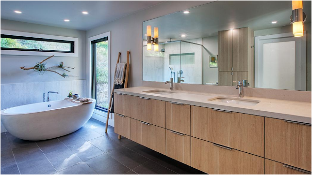 Modern bathroom with freestanding tub, double vanity, large mirror, and gray tile flooring