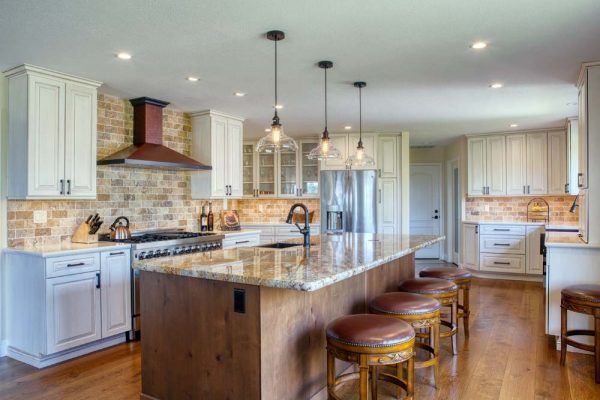 Bright modern kitchen with large island, white cabinets, stainless appliances, and wood floors