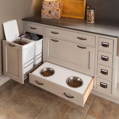 Built-in pet feeding station with pull-out bowls and trash bins in a kitchen cabinet.