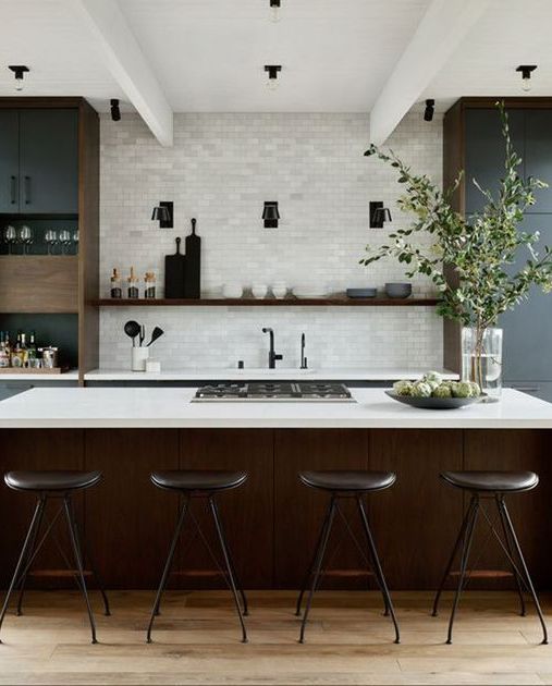 Modern kitchen with white tile wall, dark island, bar stools, and open shelves.