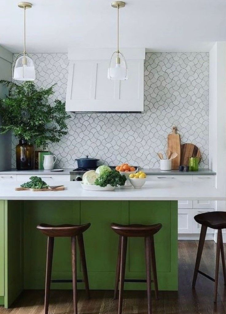 Modern kitchen with green island, white cabinets, patterned backsplash, and pendant lights.
