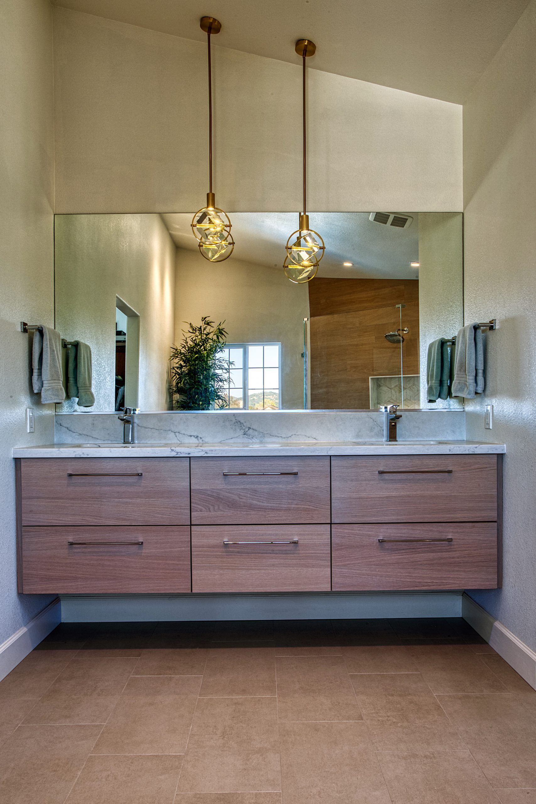 Modern bathroom vanity with double sink, large mirror, and hanging pendant lights