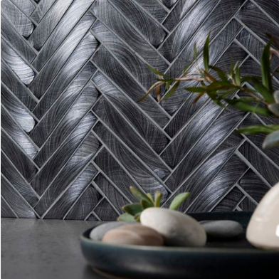 Silver leaf-patterned wall with a bowl of smooth stones and a small plant in the foreground