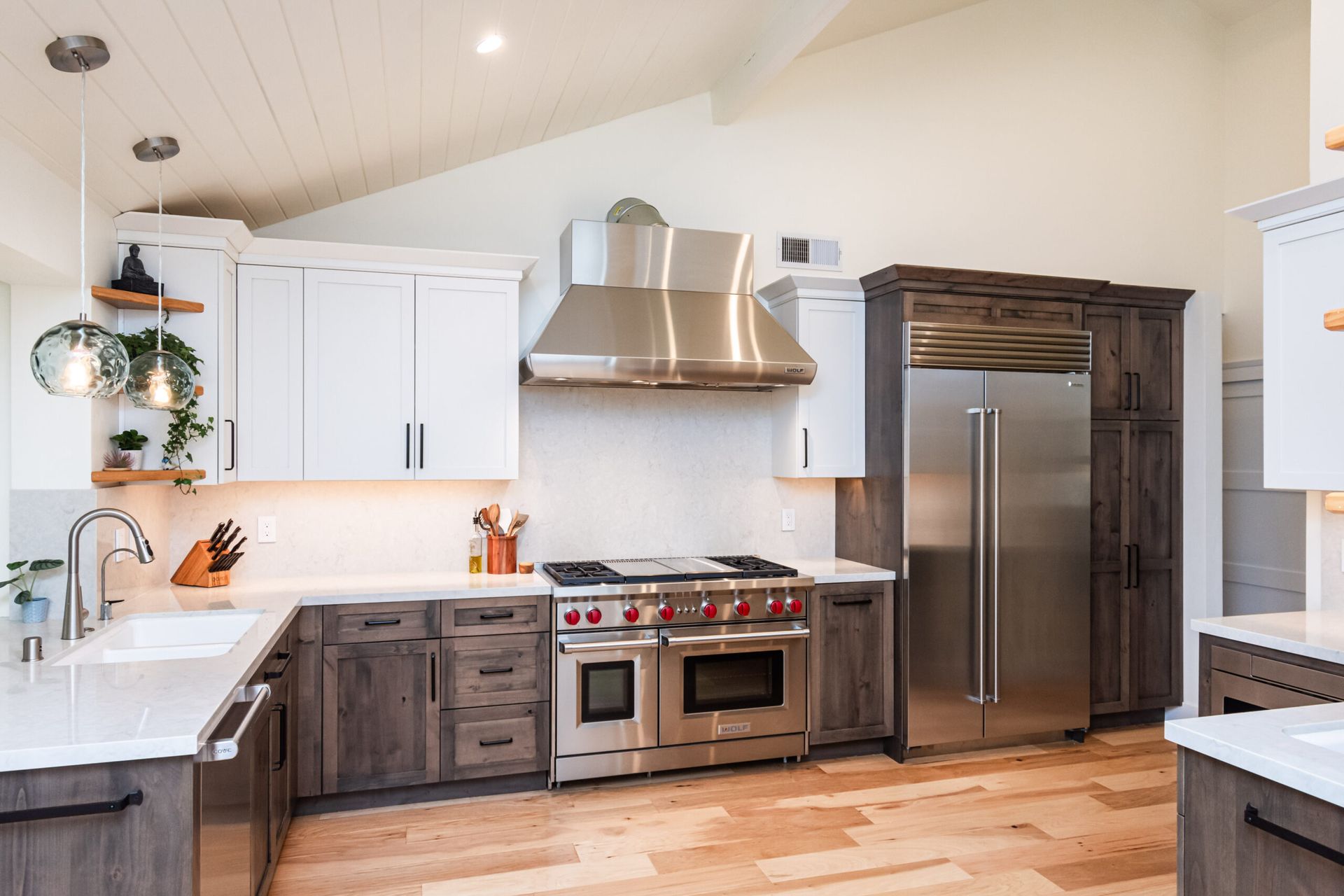Modern kitchen with white cabinets, stainless steel appliances, and wood flooring