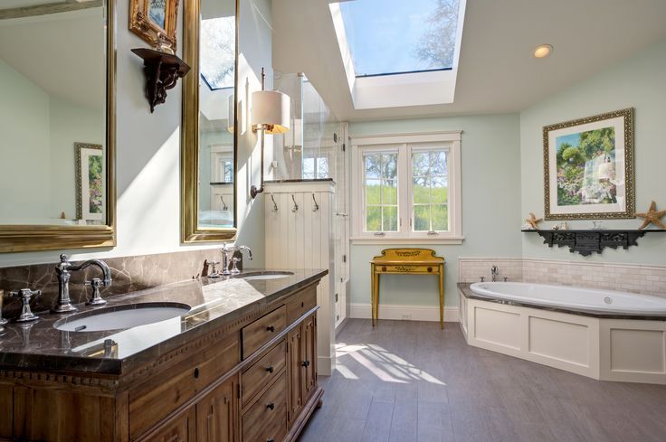 Bright bathroom with skylight, window, dark vanity, and white tub bench in a sunlit spa-like space