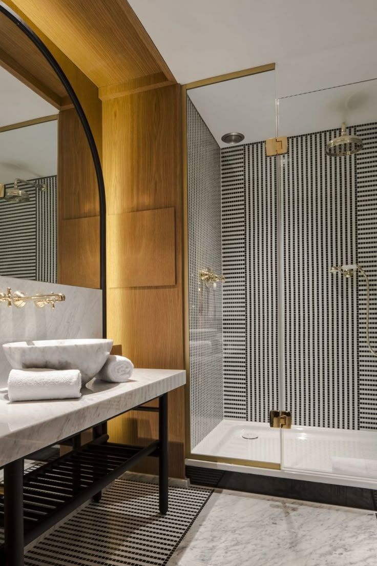 Modern bathroom with wood paneling, striped shower wall, glass partition, and gray vanity sink