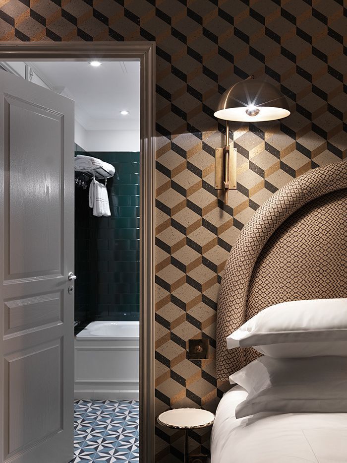 Patterned bedroom with open door to a tiled bathroom and a wicker bed headboard