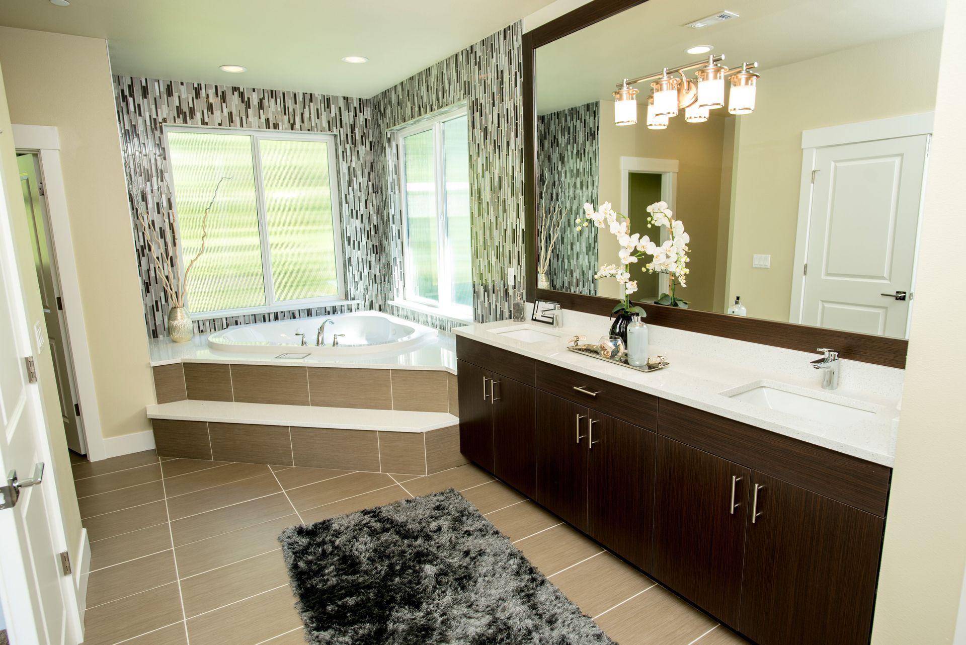Modern bathroom with large tub, double vanity, tiled floor, and black-and-white decor