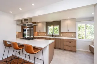 Modern minimalist kitchen with wood cabinets, white island, and blue under-cabinet lighting