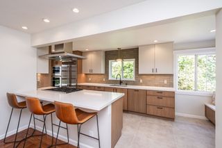 Modern minimalist kitchen with wood cabinets, white island, and blue under-cabinet lighting