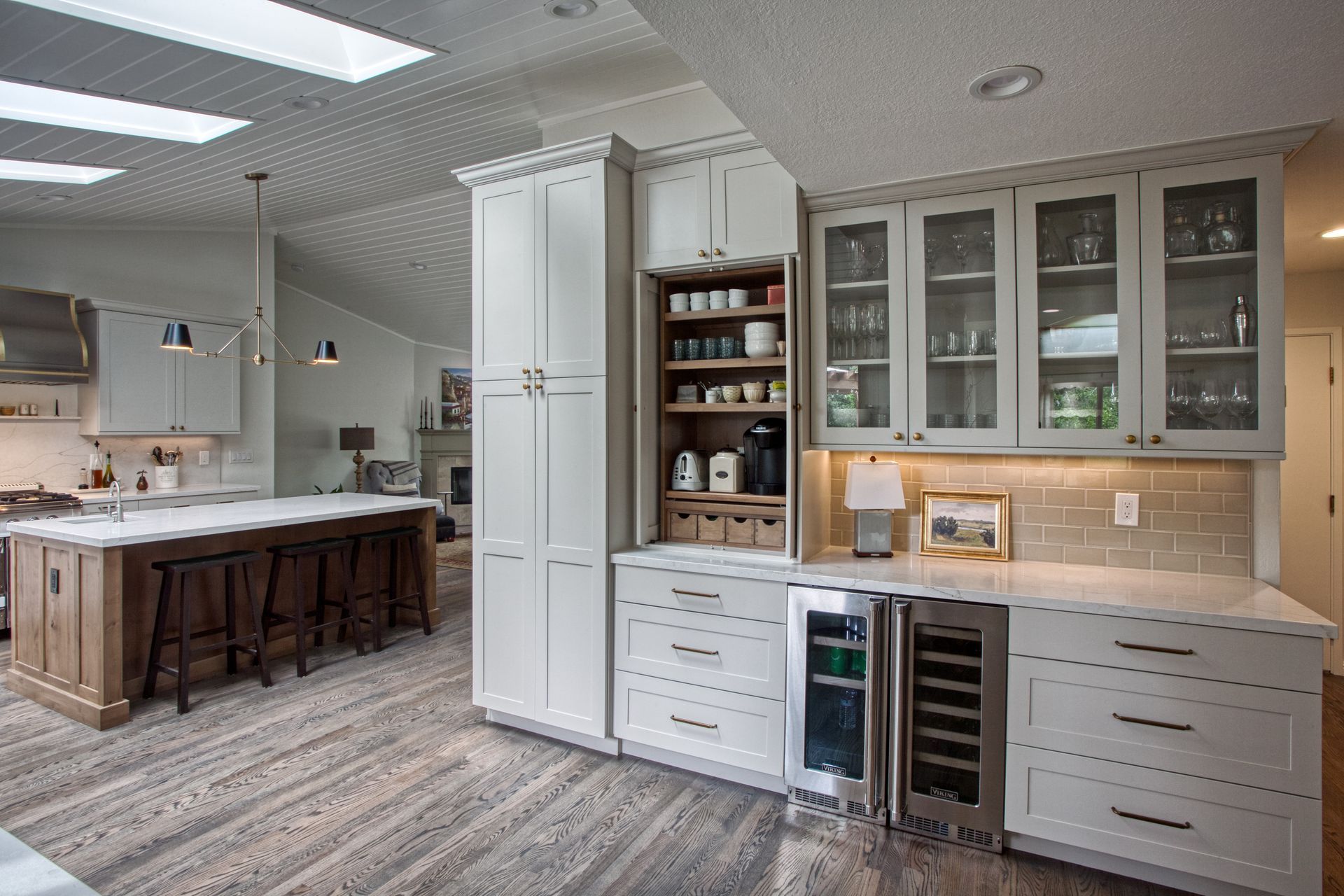 Bright white kitchen with large island, built-in cabinets, and wood floors in an open-concept home