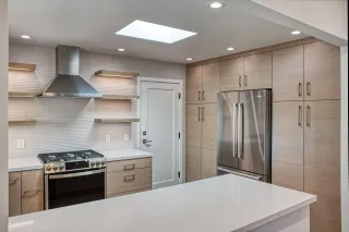 Bright modern kitchen with granite island, wood cabinets, and stainless steel appliances