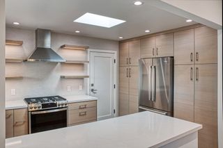 Bright modern kitchen with granite island, wood cabinets, and stainless steel appliances