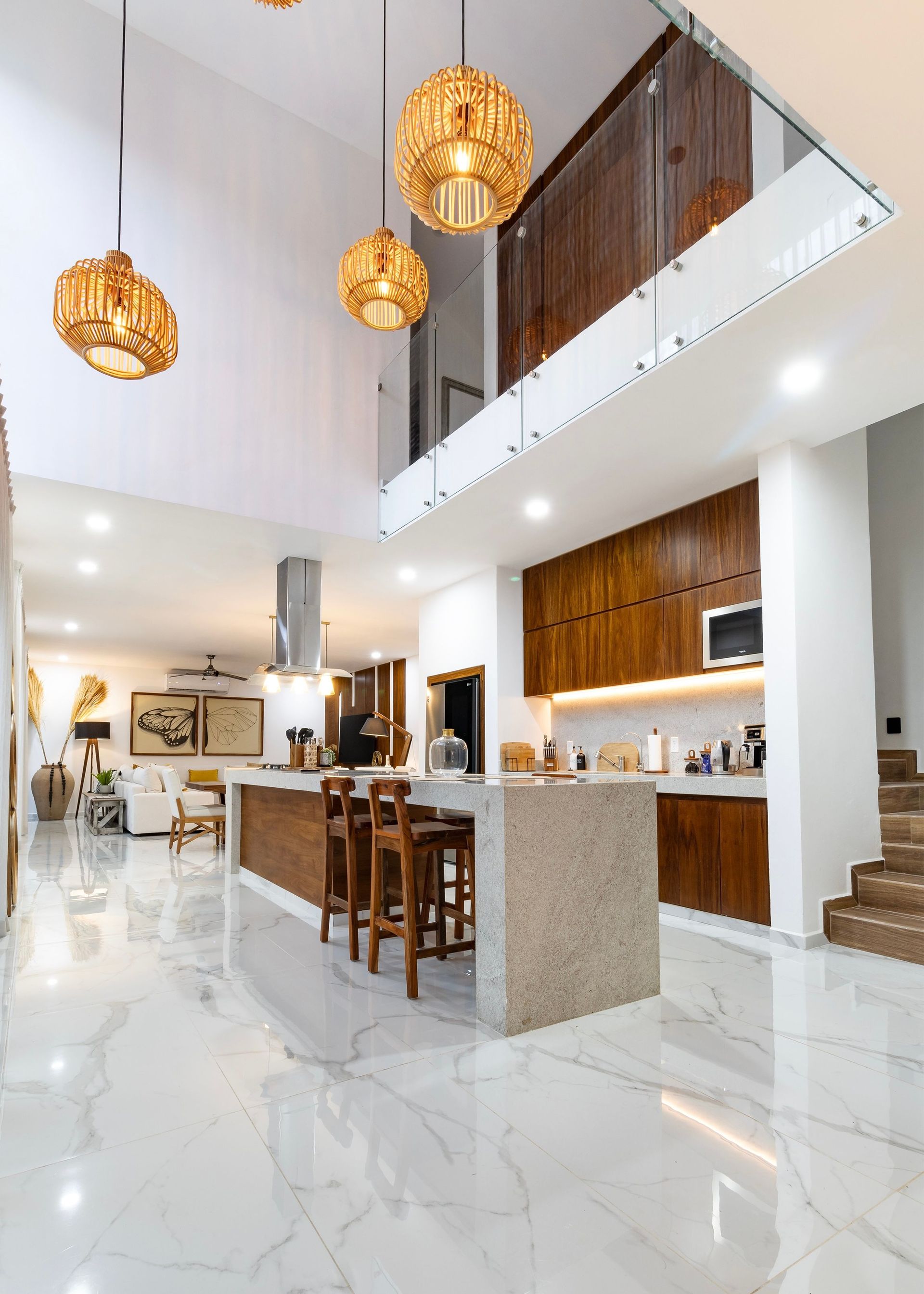 Modern open-concept kitchen and dining area with white marble floors, wood accents, and hanging pendant lights