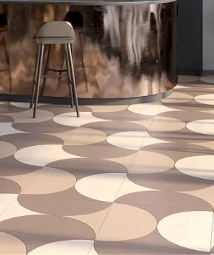 Patterned floor with circular beige and brown tiles beside a metallic bar counter and stool