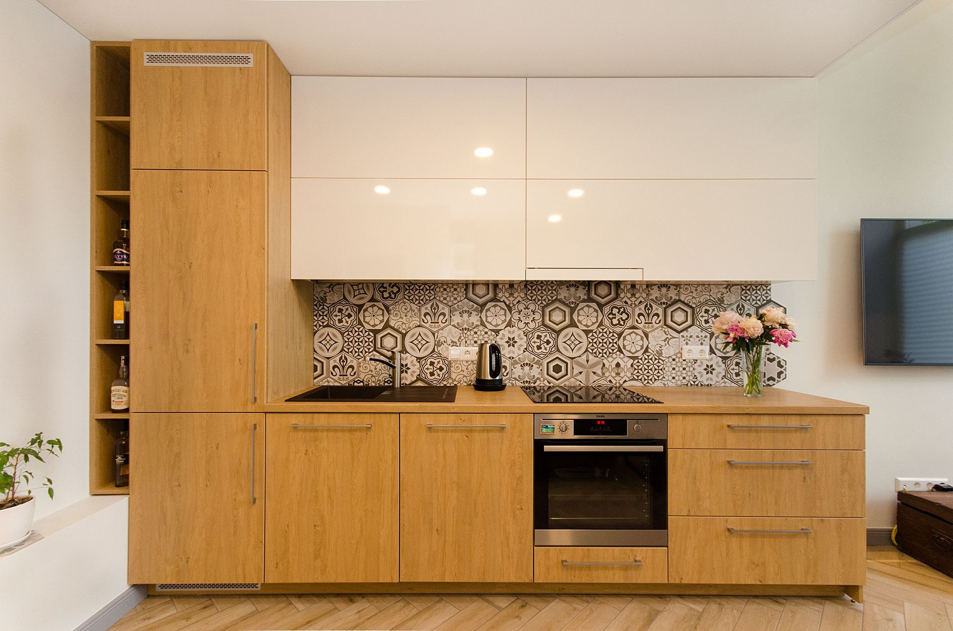 Modern kitchen with light wood cabinets, patterned backsplash, and built-in oven