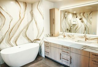 Modern bathroom with a freestanding tub, double vanity, and wavy gold-patterned wall tiles