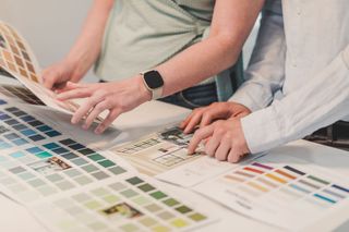Hands reviewing color swatches and printed design samples on a table