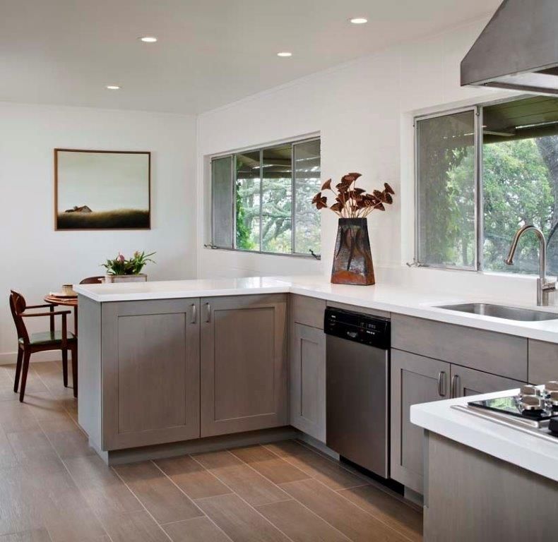 Modern kitchen with gray cabinets, white counters, large windows, and a stainless steel dishwasher