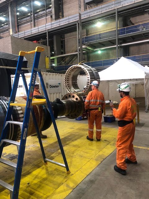 a group of men are working on a large piece of equipment in a factory .
