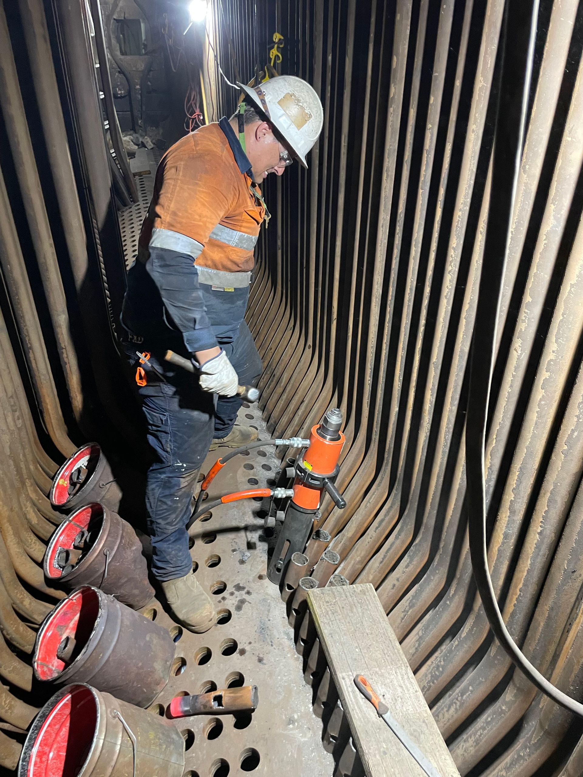 A man is working on a pipe in a tunnel.