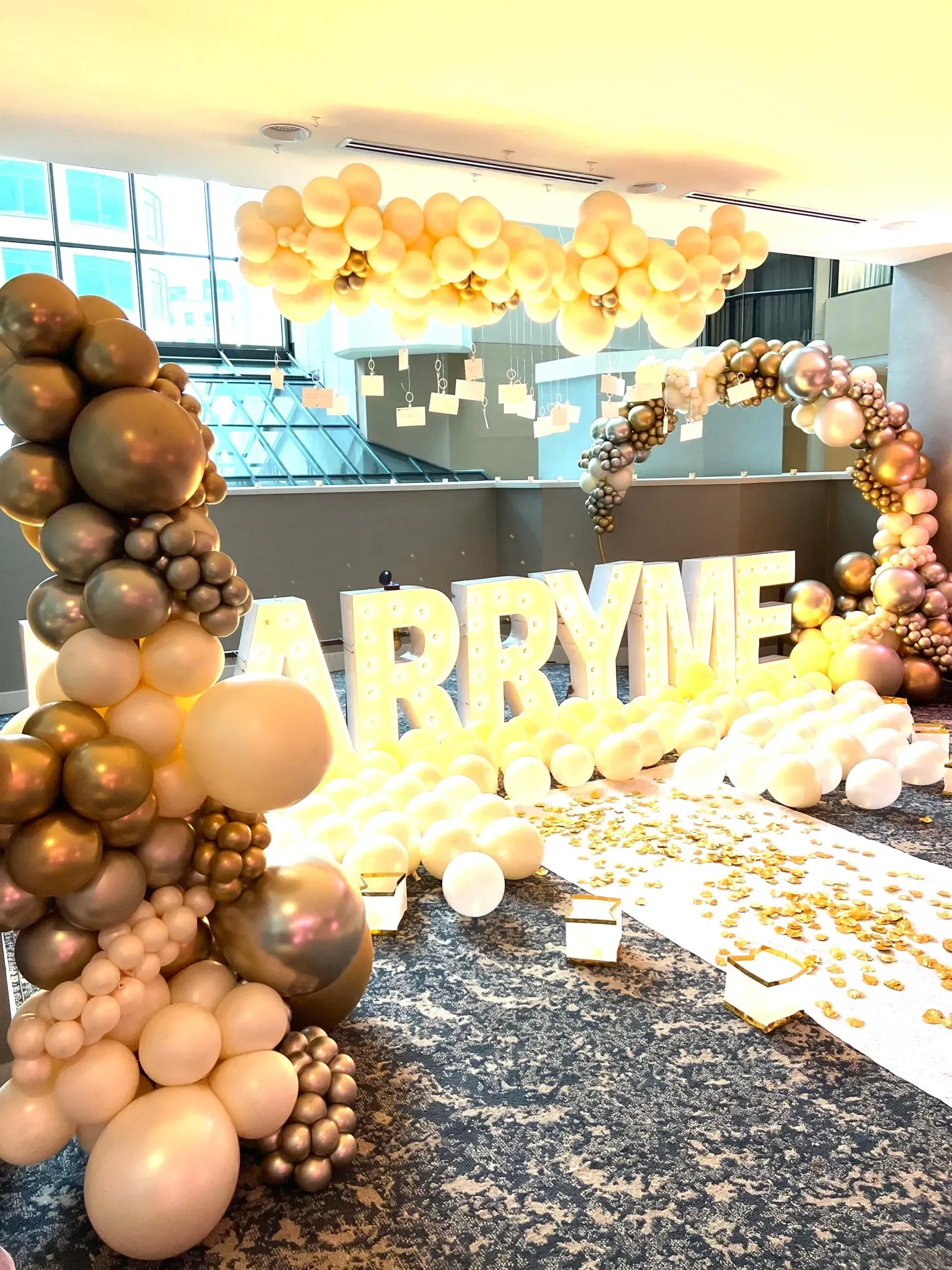 A room filled with balloons and a sign that says `` marry me ''.