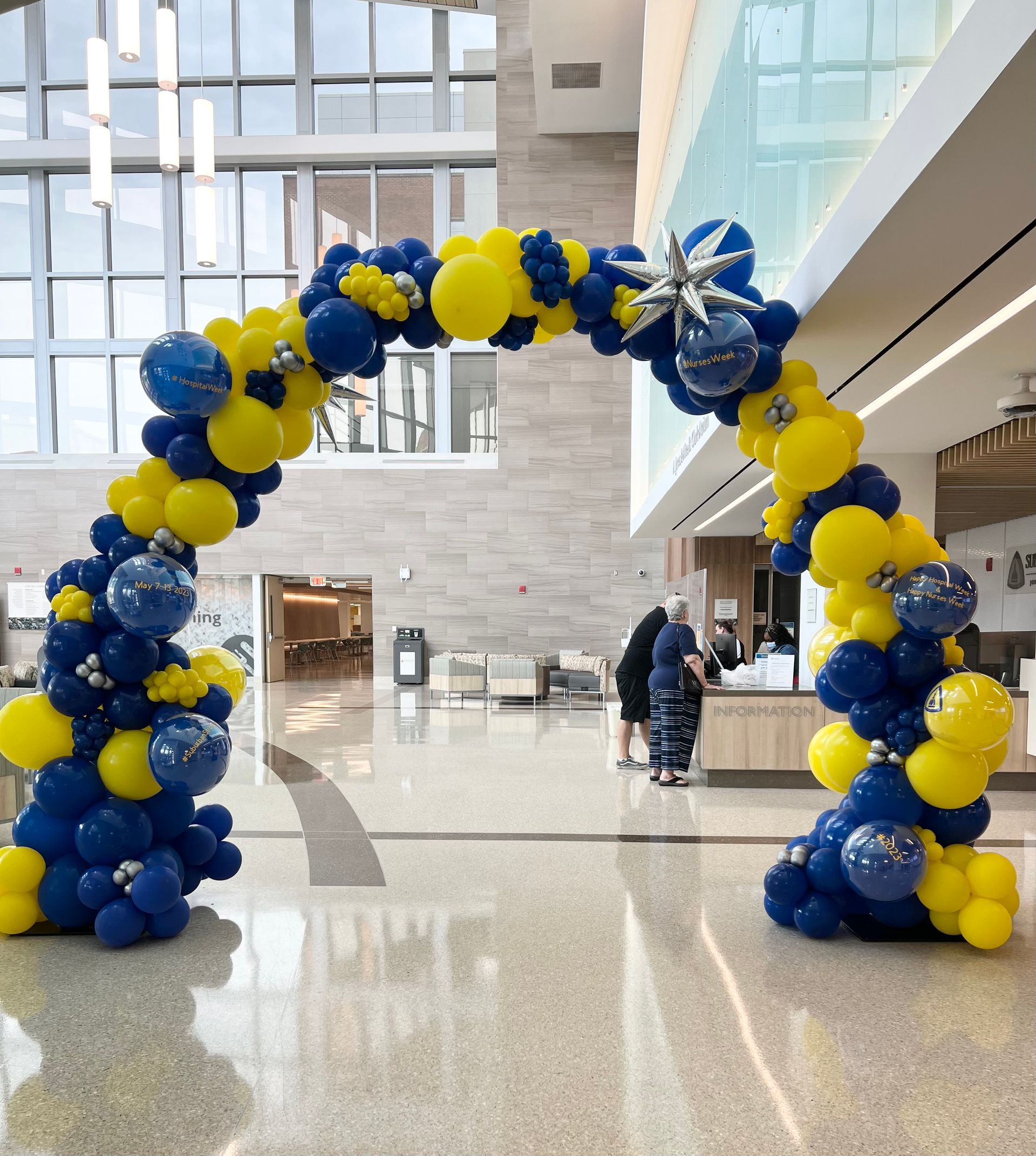 A large arch made of blue and yellow balloons in a lobby