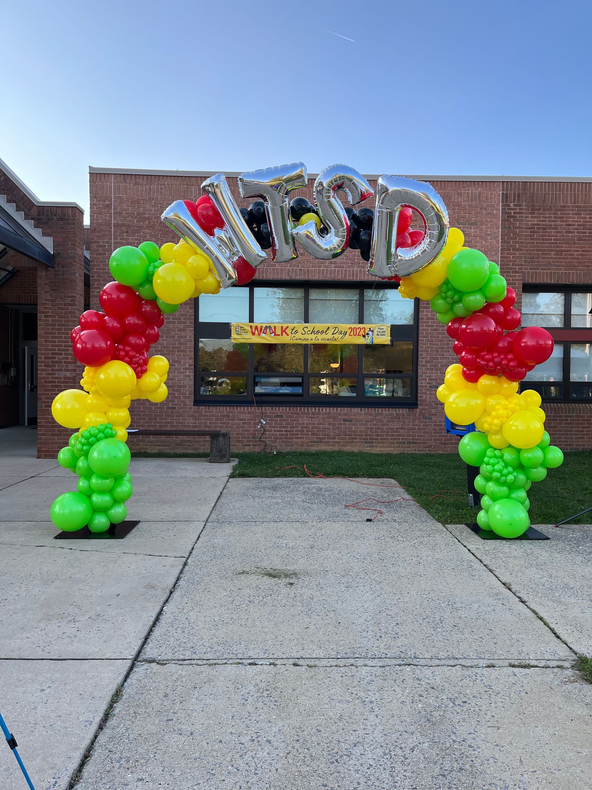 A balloon arch is in front of a brick building.