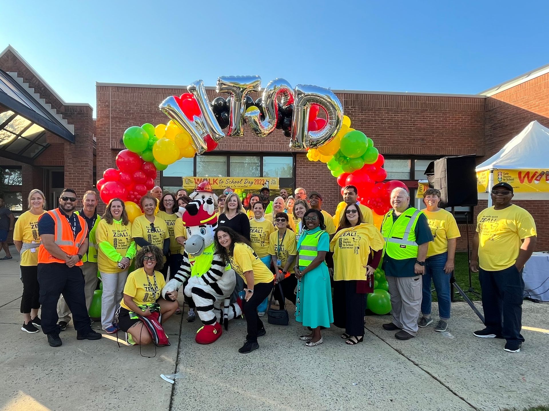 A group of people are posing for a picture in front of a building with balloons.