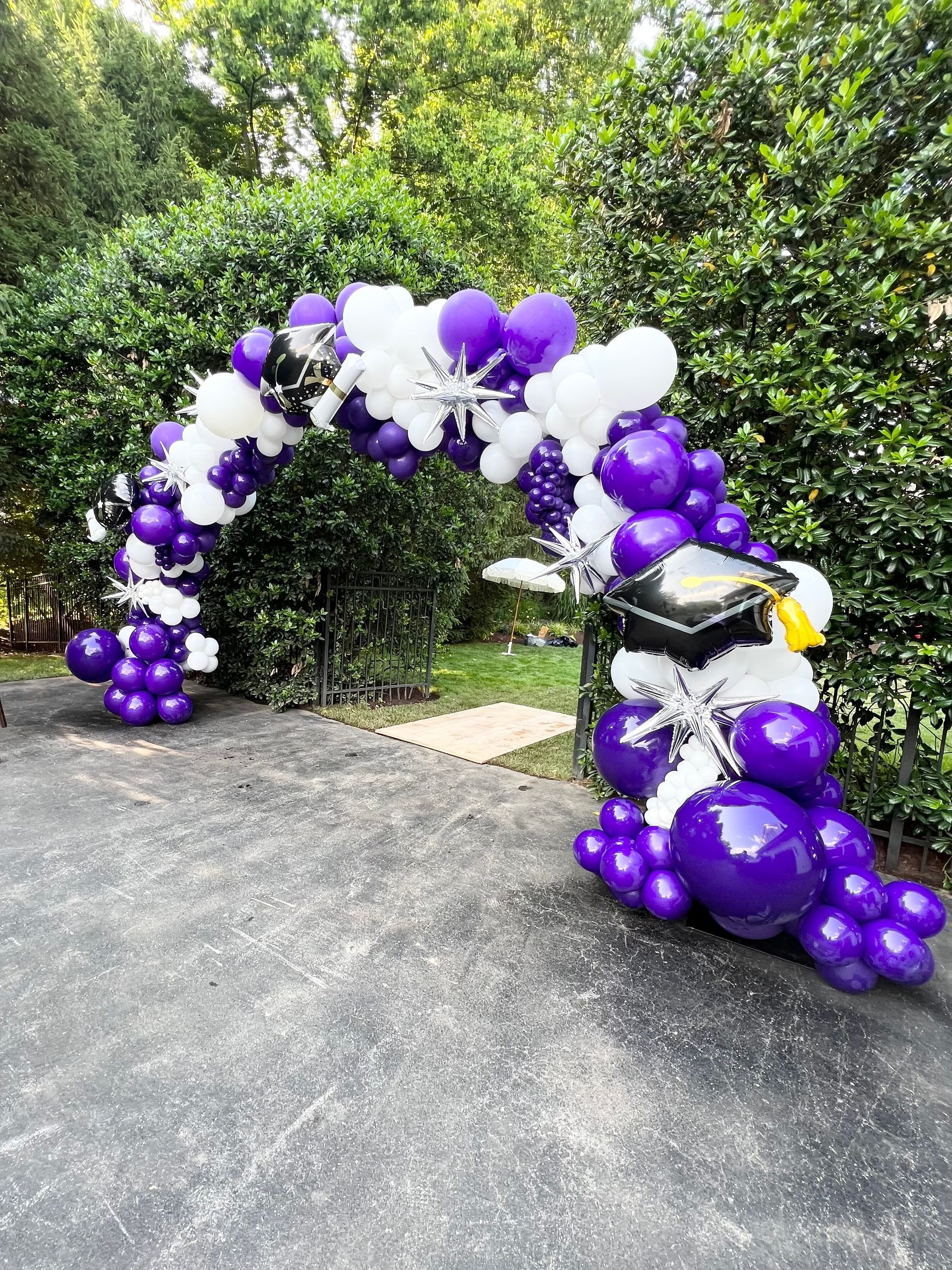 A purple and white balloon arch with a graduation cap on it.