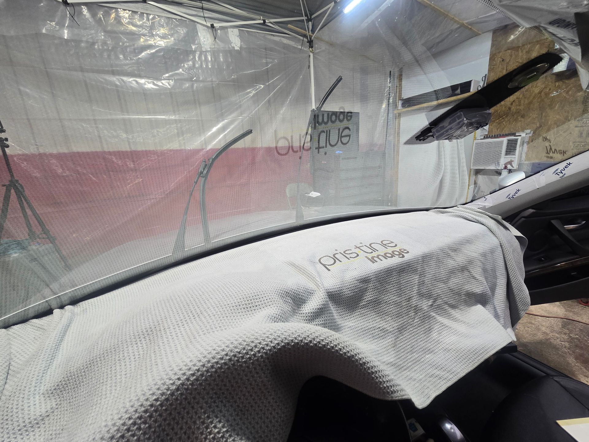 Car windshield covered in white protective fabric inside an auto shop