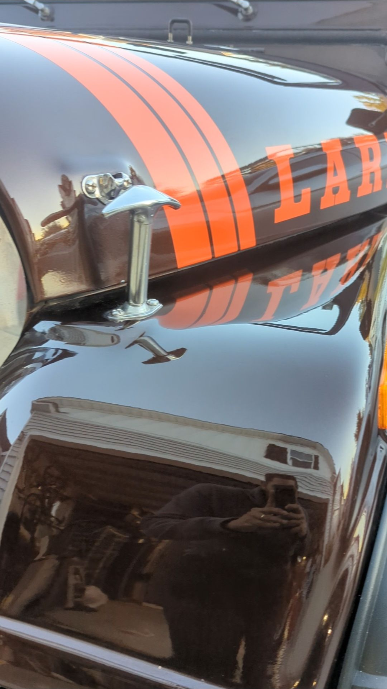 Black vehicle with orange racing stripes and roof cargo box, seen close up.