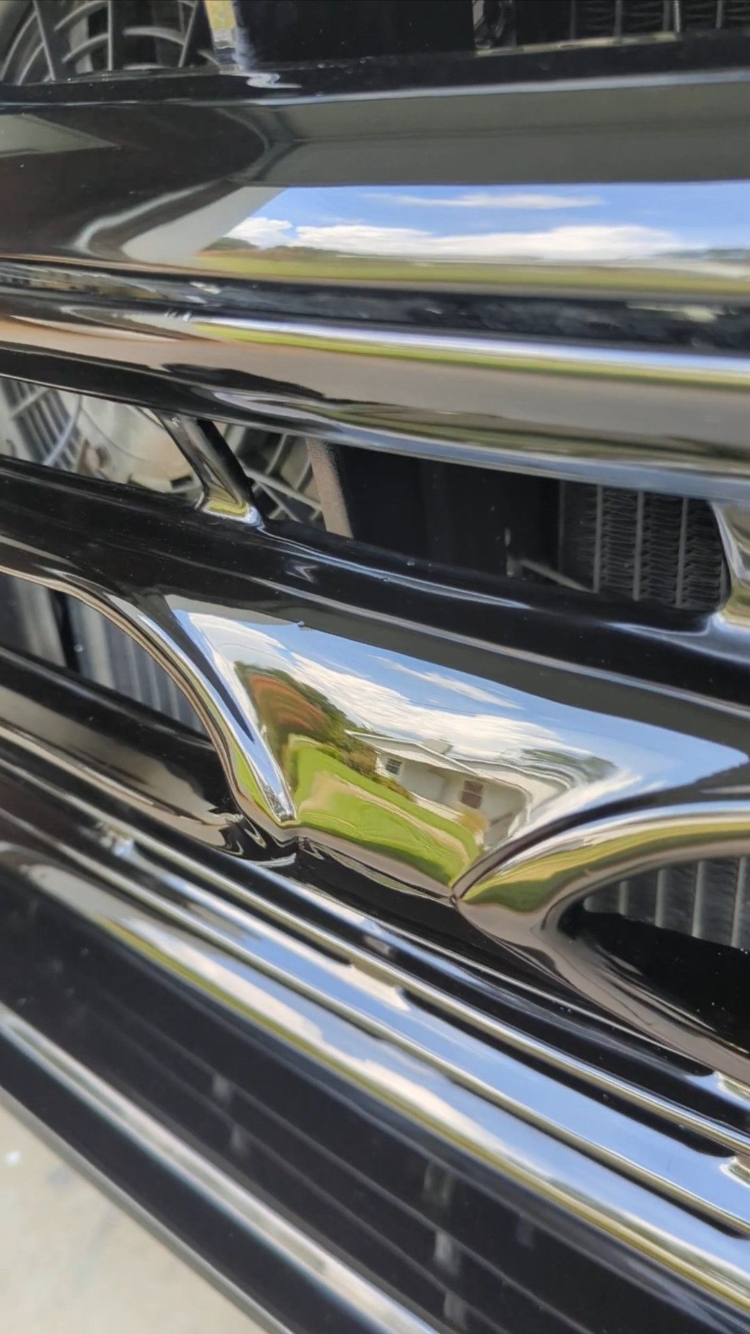 Close-up of a chrome car grille with reflective horizontal slats and black accents