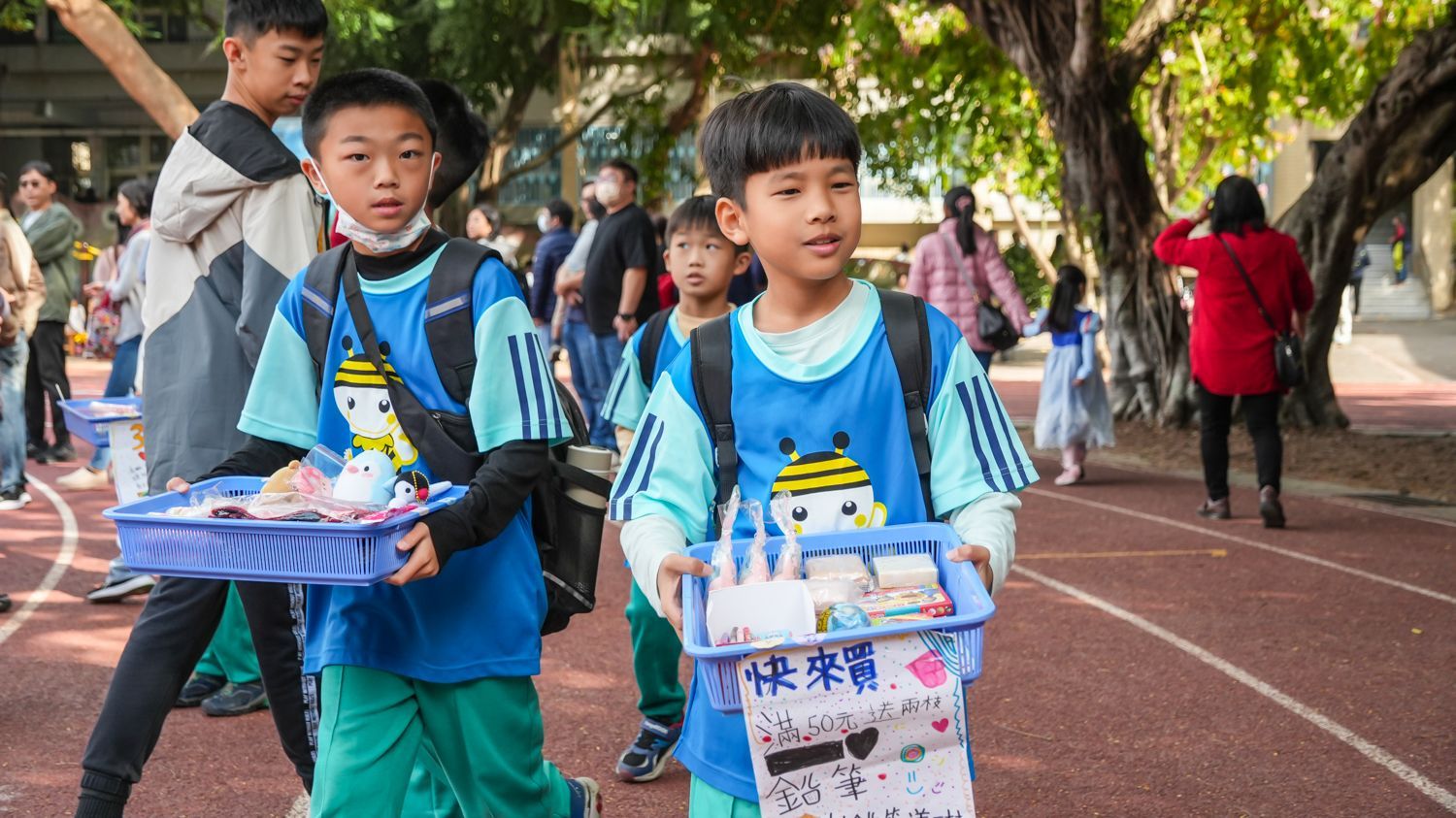 一群小男孩端著托盤沿著小路走。