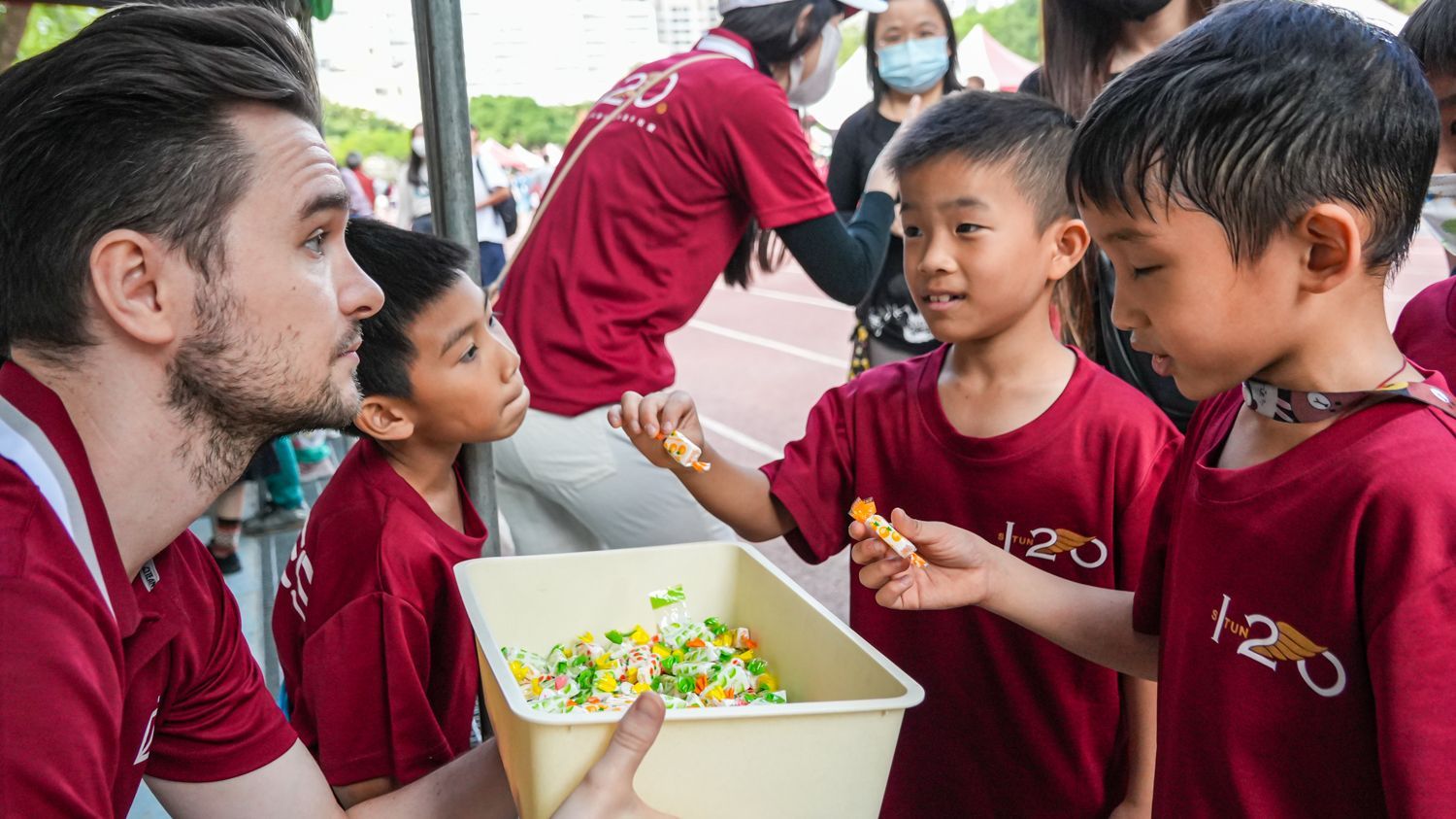 一個男人正在給一群小男孩提供食物。
