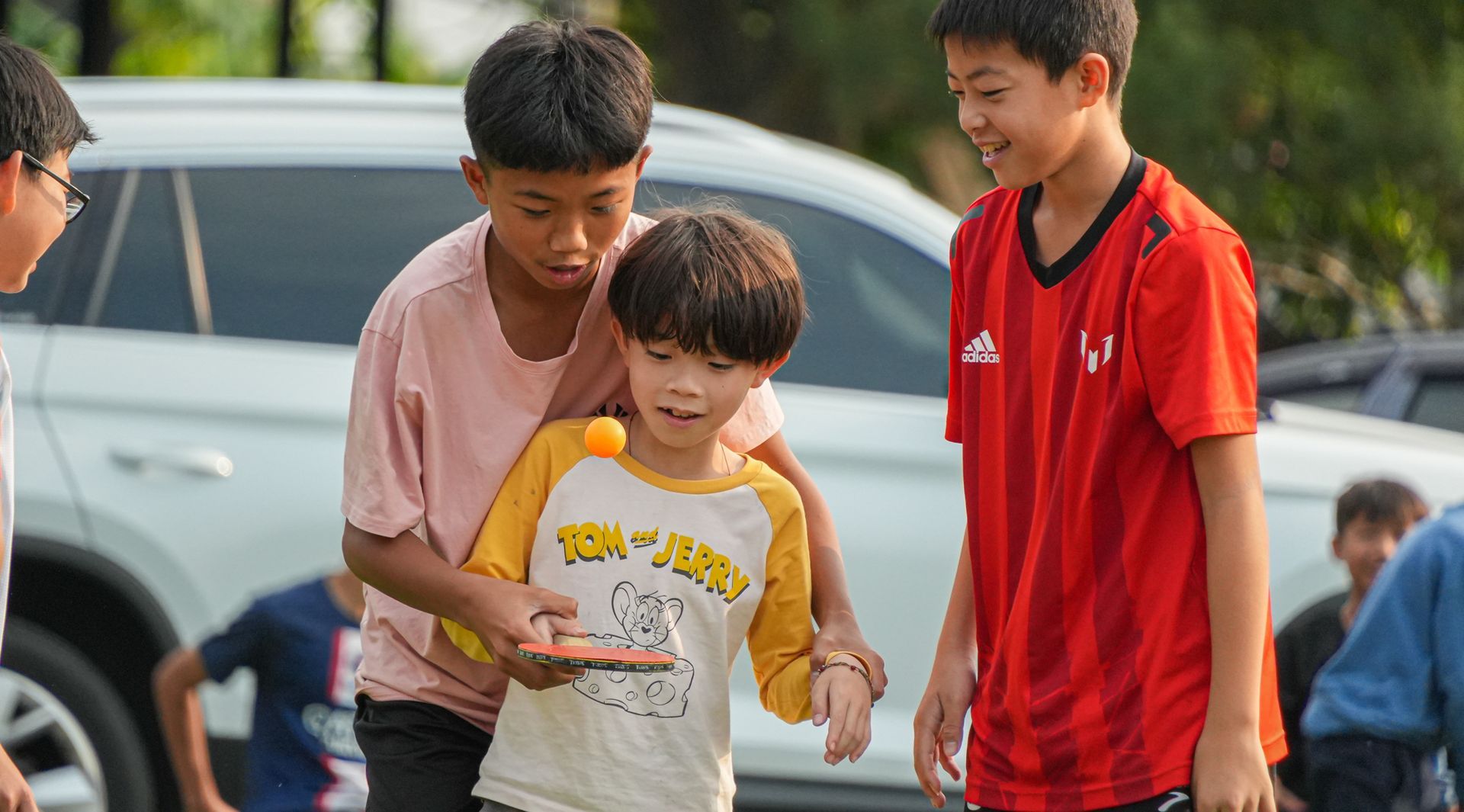 一群小男孩正在停車場打乒乓球。