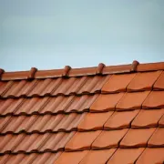 A split view of a roof showing a weathered, darker tiled section on the left and a clean, vibrant orange tiled section.