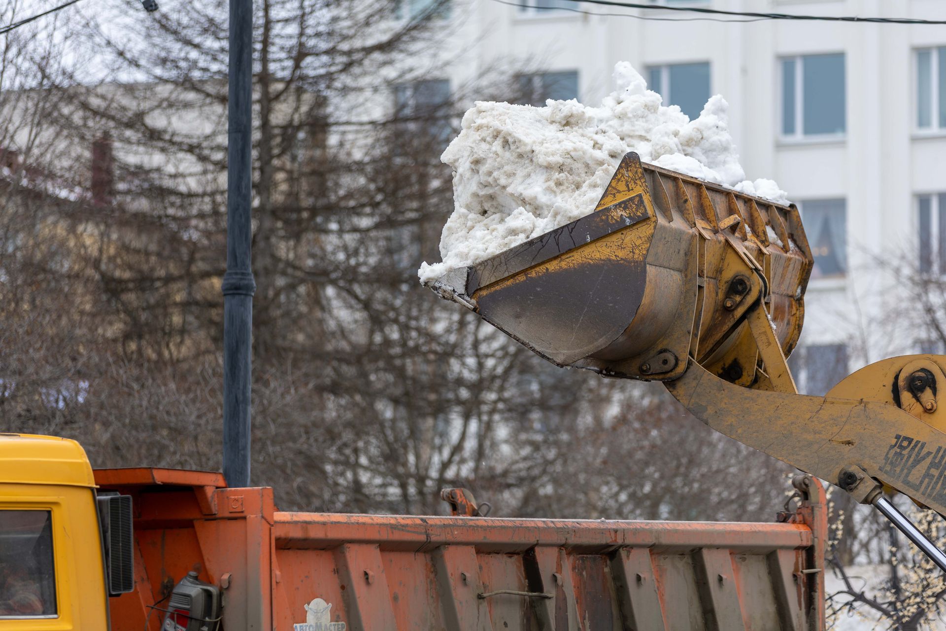 Orange CAT excavator at a construction site in front of houses behind a fence