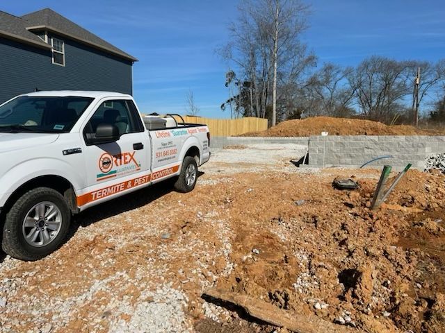White work truck parked on a construction site; building foundation in background.