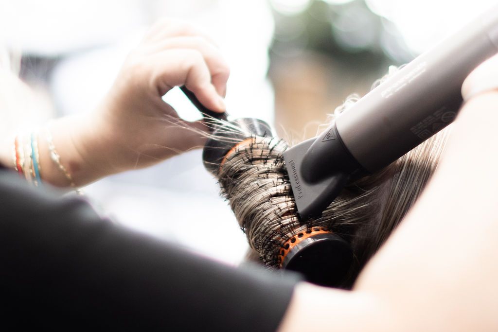 Wavy blue-black hair with soft curls, seen from behind in a salon setting.