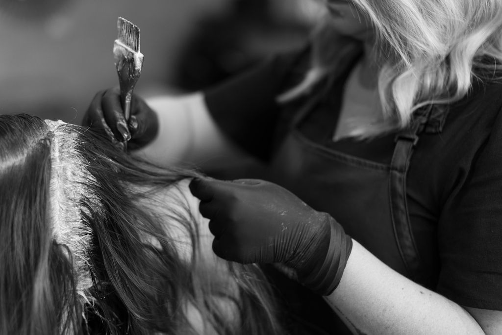 Woman reclining at a salon shampoo sink while a stylist washes her hair