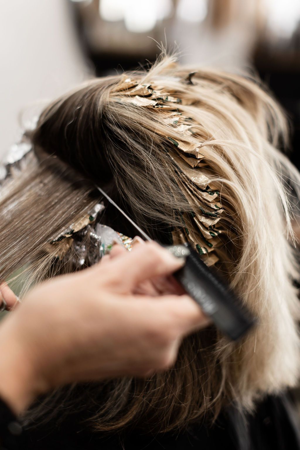 Stylist arranging a blonde updo with hairpins in a salon